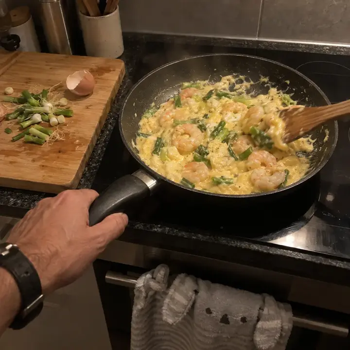 Revuelto de gambas y ajetes en la sartén, removido con una espátula de madera